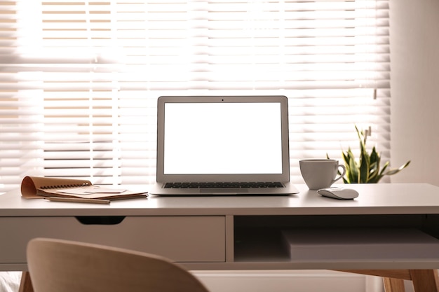 Laptop op bureau bij raam op kantoor Comfortabele werkplek