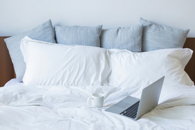 Photo laptop pc and cup of coffee on the bed