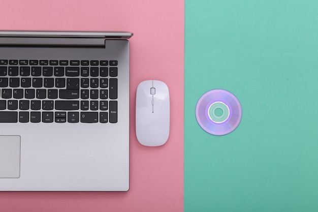 Laptop, Pc mouse with cd on pink blue background. Top view