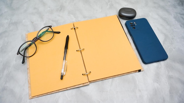 A laptop pen glasses and a pen are on a table next to a notebook