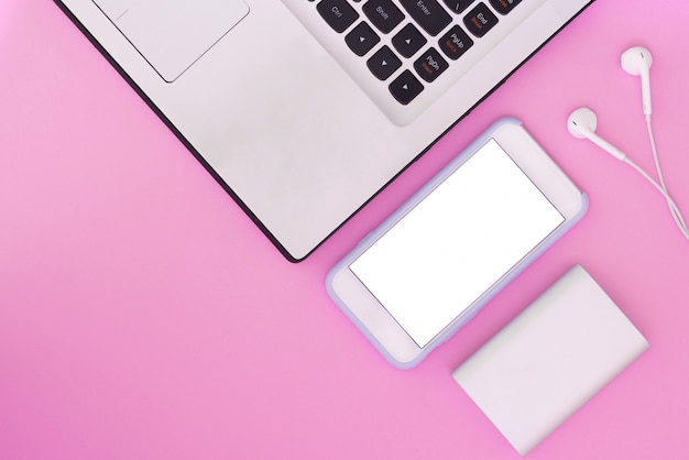 Laptop, phone, headphones and power bank on a pink background. Flat Lay composition and place for text. Top view.