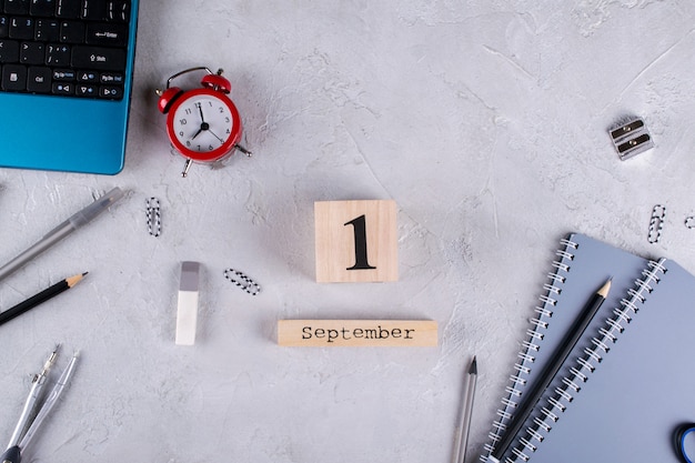 Laptop, red alarm clock and supplies, wooden calendar