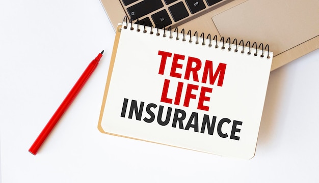 白い背景にラップトップの赤ペンとメモ帳のテキスト「定期生命保険」