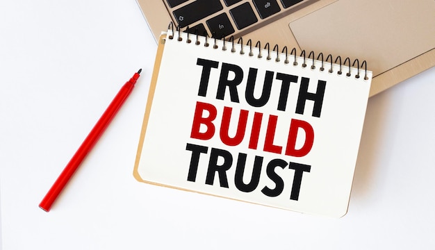 Laptop red pen and notepad with text truth build trust in the white background