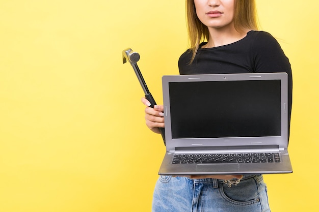 Laptop reparatie vrouw met hamer en laptop op gele achtergrond