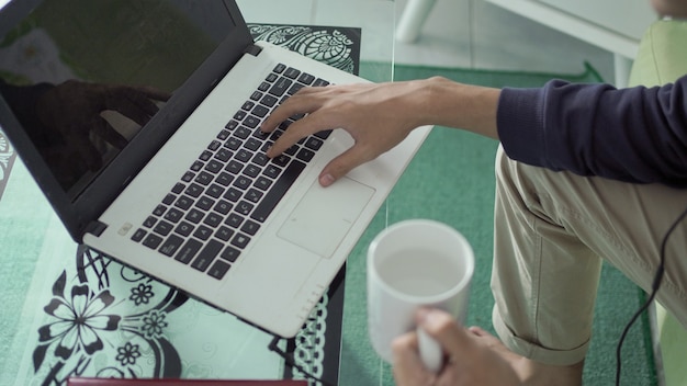 Laptop screen and cup of drink by asian man