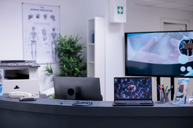 Foto schermo del laptop sulla reception vuota che mostra un campione di cellula di coronavirus. immagini di laboratorio scattate con il microscopio visualizzate sul monitor di un computer portatile presso il centro di prevenzione medica.