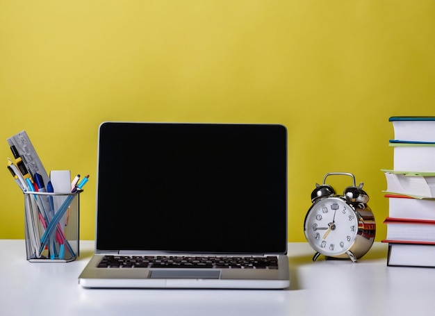 A laptop sits on a desk with a cup of pencils and a clock.