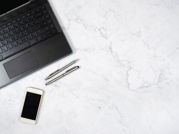 Laptop smartphone en zilveren pen op de marmeren tafelblad weergave kopieerruimte