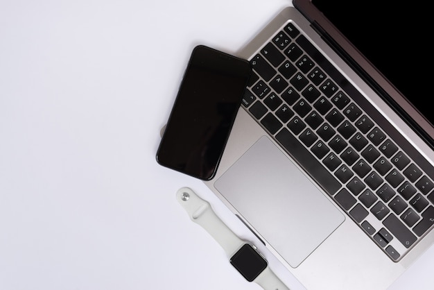 laptop smartwatche and phone on white table