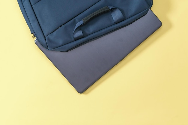 Laptop steekt uit een blauwe tas op een gele achtergrond Accessoires voor studie, zaken en werk