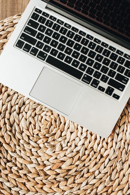 Laptop on straw. Flat lay, top view minimal home office desk workspace