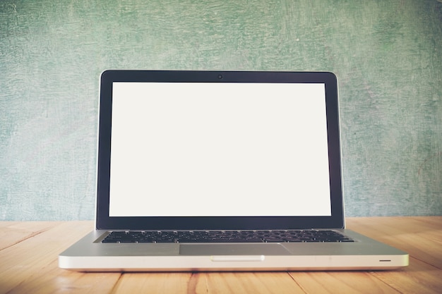 Laptop on table, on blackboard background,blank screen