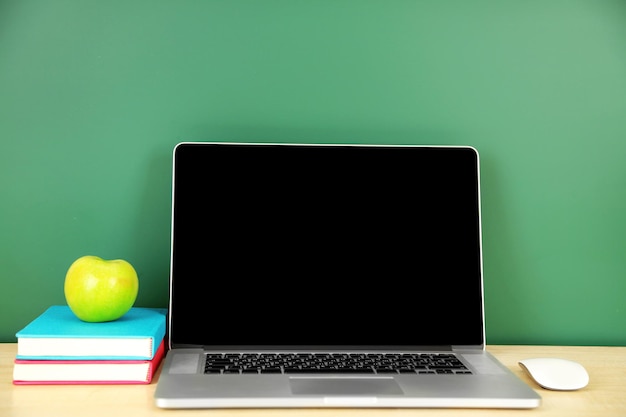 Laptop on table on green blackboard background