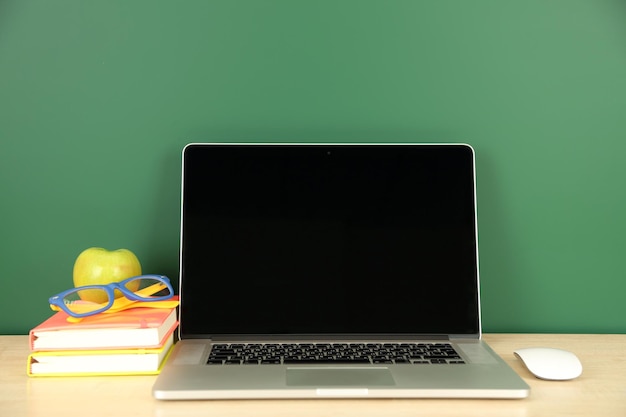 Laptop on table on green blackboard background