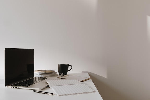 Laptop on table with coffee cup, paper sheet