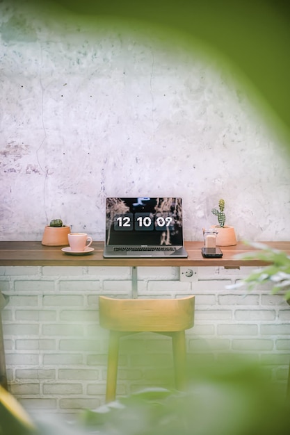 A laptop on a table with a cup of coffee and a cactus tree decoration in a cafe