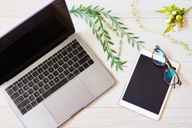 Laptop, tablet and glasses on a wooden table