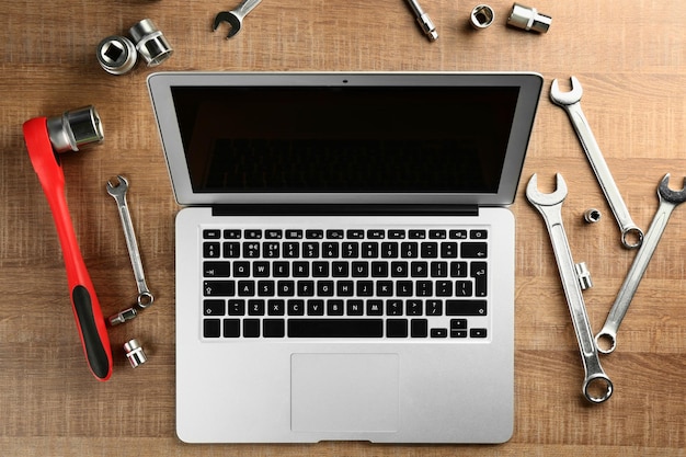 Photo laptop and tools for car repair on wooden table