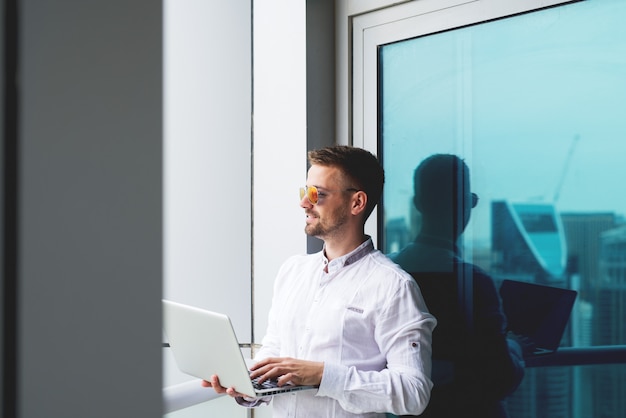 Laptop van de zakenmanholding bureaubalkon het werken.