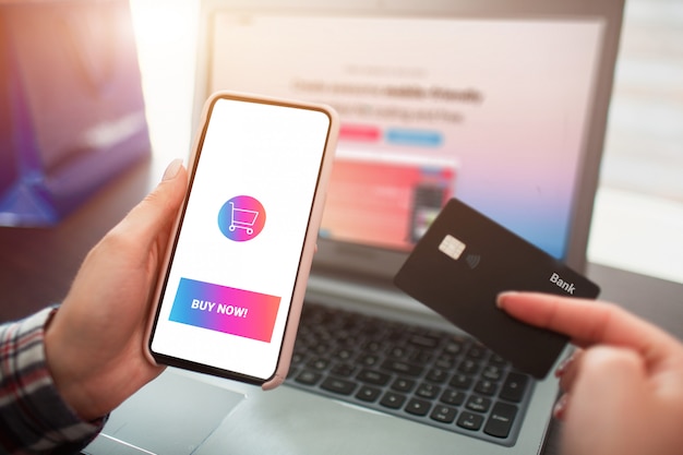Laptop van het close-upplan smartphone en creditcard in handen. online winkelen en thuisbezorging concept.