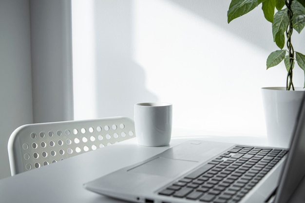 Laptop white cup with coffee on a white table Freelancers workplace