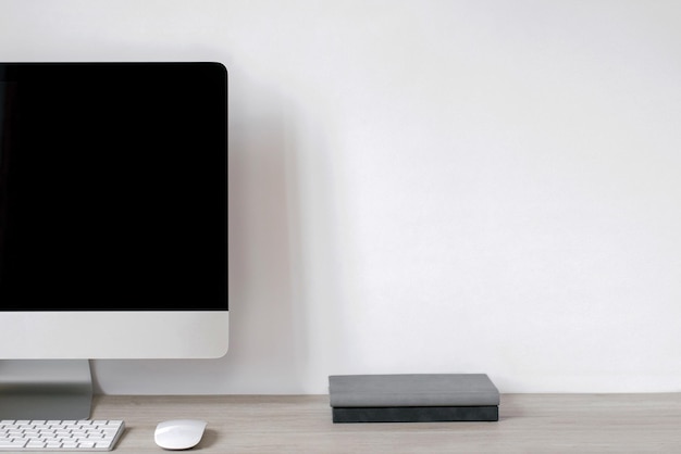 A laptop with a black blank screen and notepads stands on the table against the background