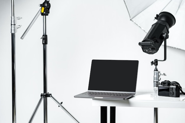 Foto laptop con schermo nero e attrezzature fotografiche in studio fotografico