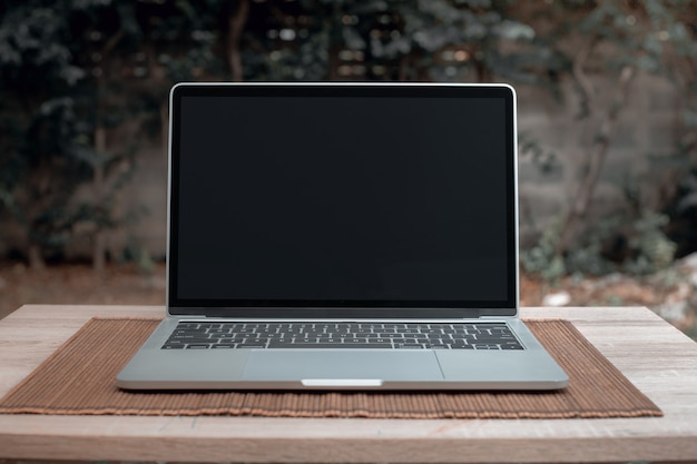 Laptop with black screen on wooden table