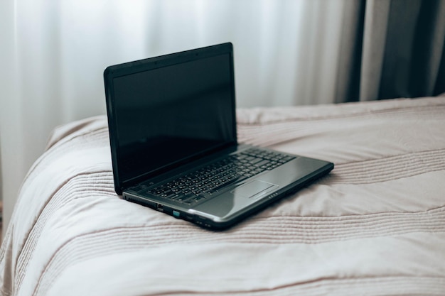 침대 프리랜스 컨셉의 스타에서 온라인 쇼핑을 하는 아늑한 침대 복사 공간에 빈 검은색 화면이 있는 노트북...