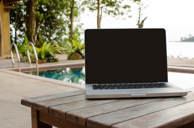 Laptop with blank black screen on wooden table outdoor
