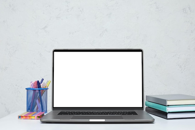 Foto laptop con schermo vuoto su mockup di spazio di lavoro dell'ufficio bianco