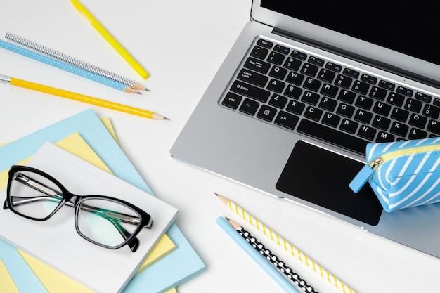 Laptop with blank screen glasses and stationery on white modern table