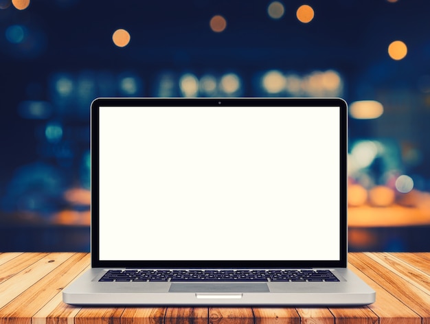 Laptop with blank screen on table, cafe blurred wall.