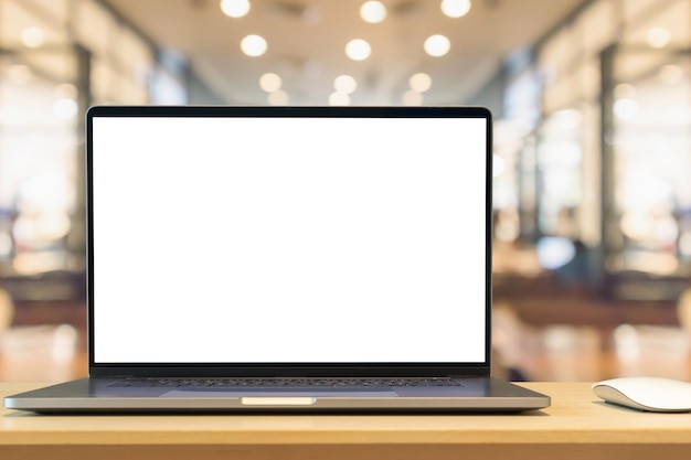 Laptop with blank screen on wood table with cafe coffee shop blur background