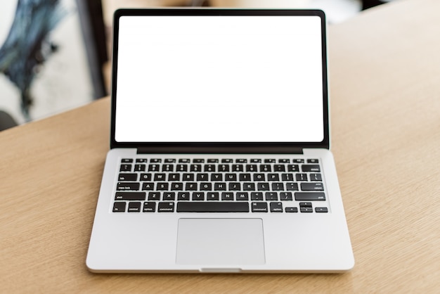 Laptop with blank screen on wooden table and blurred background