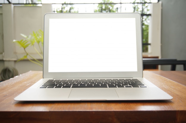 Laptop with blank screen on wooden table in front of coffeeshop cafe - technology concept