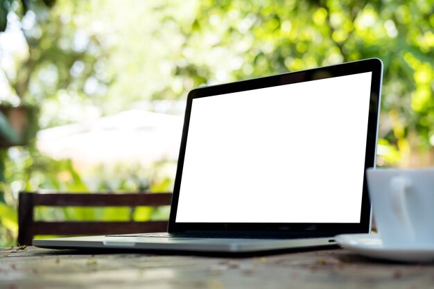 Laptop with blank white screen and coffee cup on vintage wooden table