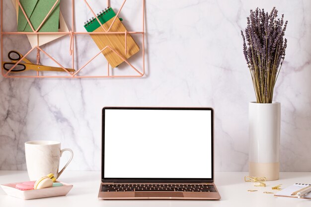 Laptop with blank white screen on home office desk interior. stylish workplace mockup table view.