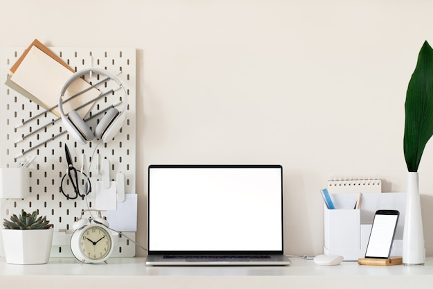 Laptop with blank white screen on office desk interior. Stylish gold workplace mockup table view.