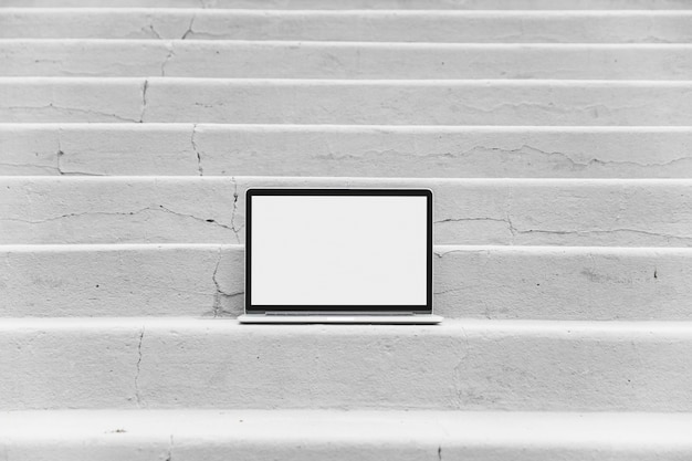 Laptop with blank white screen on staircase