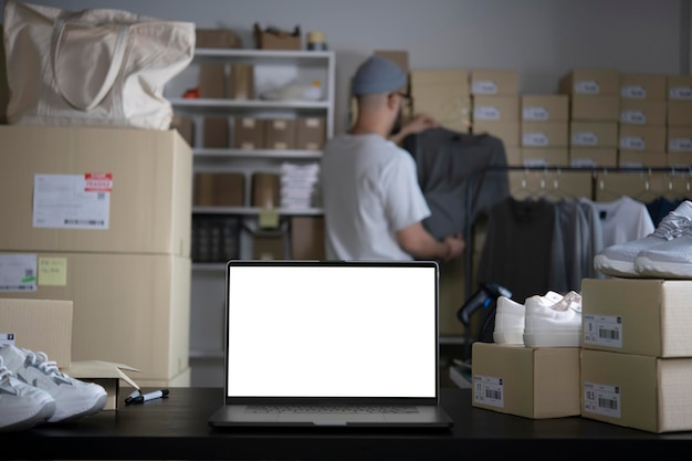 倉庫のデスクトップに立っている空白の白い画面とラップトップ