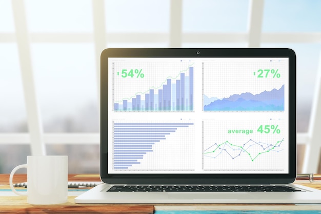 Photo laptop with business graph on the wooden desk with cup of coffee in a sunny office