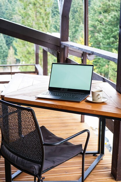 Laptop with a cup on a wooden table on the terrace