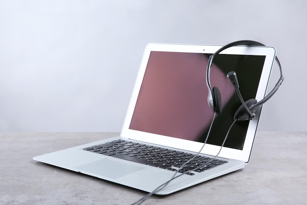 Laptop with headset on grey background