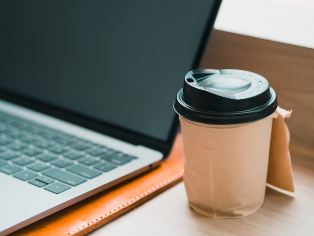 Laptop with hot cup of coffee on the bar of the cafe.