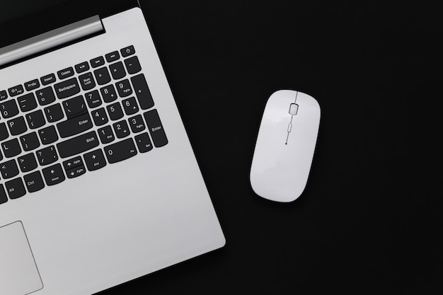 Laptop with pc mouse isolated oin black background. Online workspace. Remote work. Studio shot. Top view. Flat lay