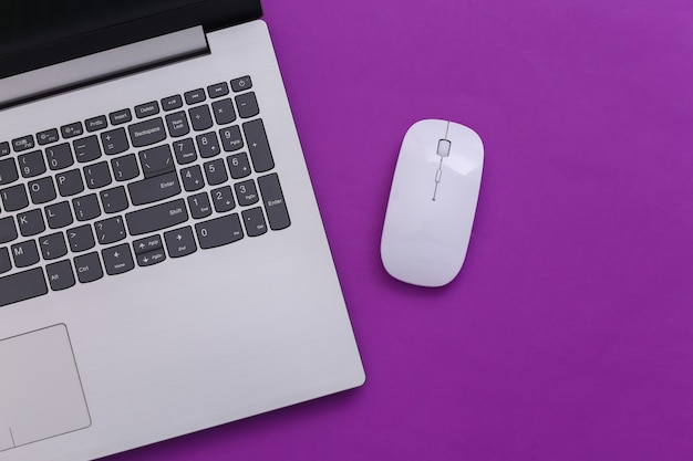 Laptop with pc mouse on purple paper background. Online workspace. Remote work. Studio shot. Top view. Flat lay