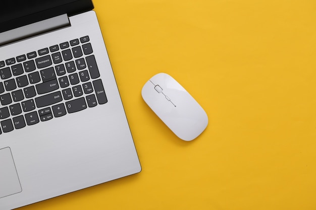 Laptop with pc mouse on yellow paper background. Online workspace. Remote work. Studio shot. Top view. Flat lay