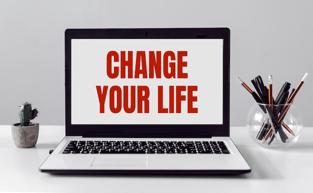 Laptop with text CHANGE YOUR LIFE on modern office background